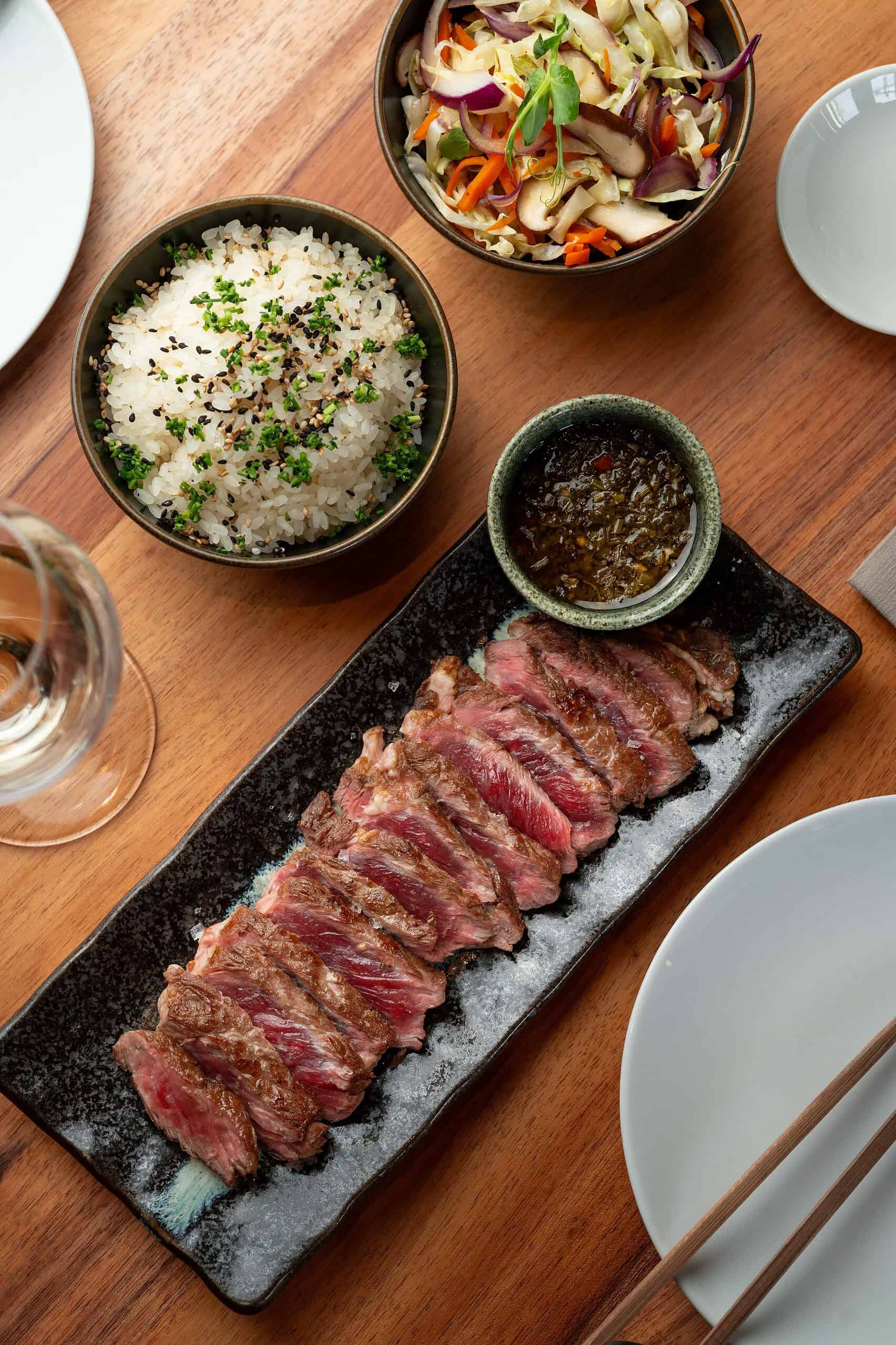 Pratos de arroz, salada e carne fatiada no restaurante IKEDA. 